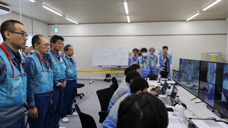 Workers at Fukushima watch the retrieval operation from the control room. Workers at Fukushima watch the retrieval operation from the control room.
