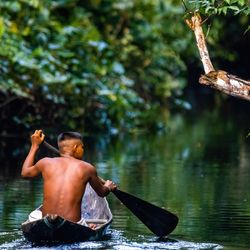 Native man sailing in AMazon river rainforest in handmade boat