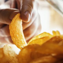 Hand takes out potato chips, from inside the package