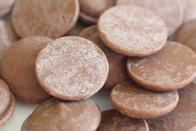 milk chocolate buttons with a white patchy coating on the surface, caused by fat or sugar bloom