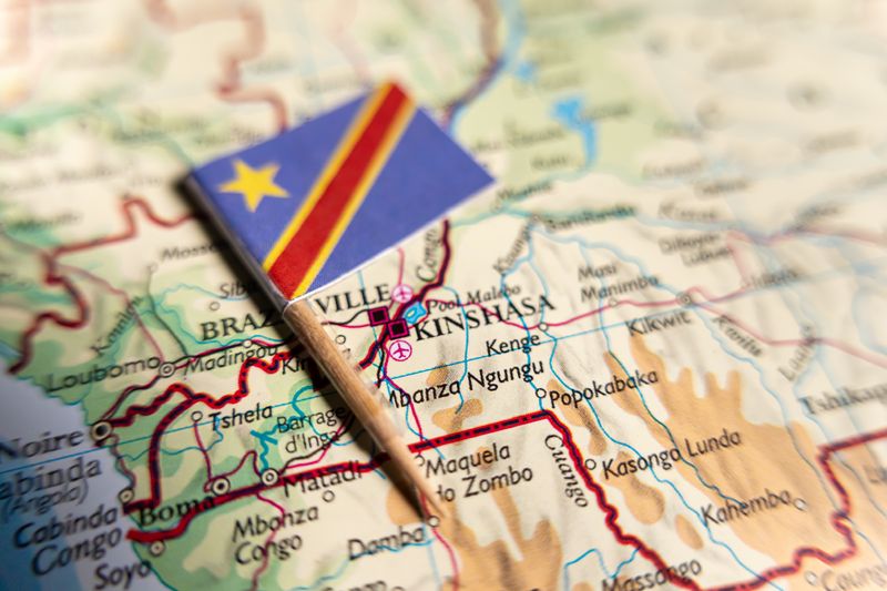 small flag of the democratic republic of the congo, attached to a cocktail stick and laid on top of a map of the country