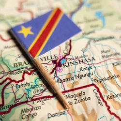 small flag of the democratic republic of the congo, attached to a cocktail stick and laid on top of a map of the country