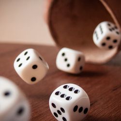 Five dice being thrown out of a cup onto a table