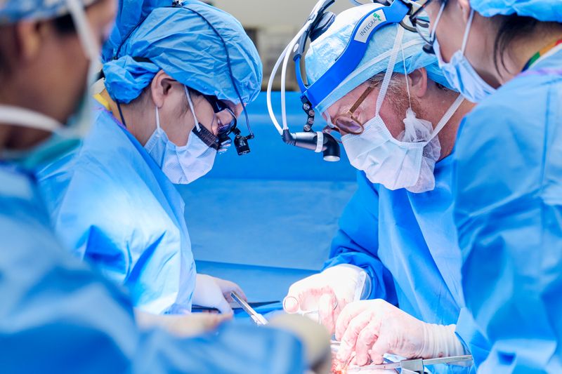 four surgeons wearing masks and other surgical gear during a transplant operation