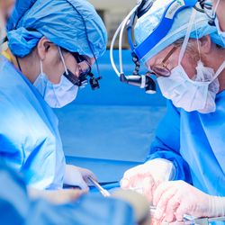 four surgeons wearing masks and other surgical gear during a transplant operation
