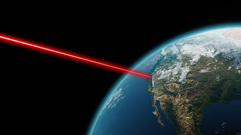 A red laser beam beams out into space from an earth satellite showing California