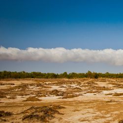 A large 'morning glory cloud' stretches across a blue sky over the Australian outback.