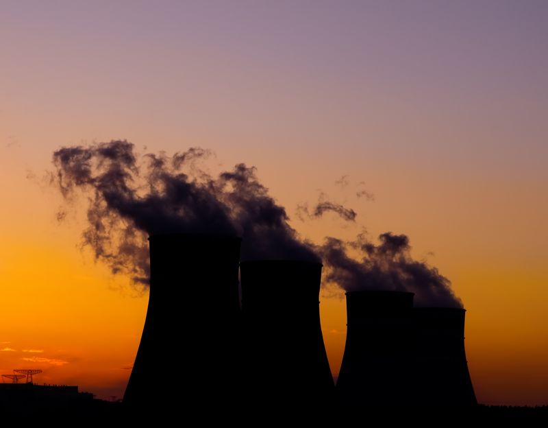 silhouette of three cooling towers of a nuclear power plant against a sunset sky