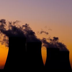 silhouette of three cooling towers of a nuclear power plant against a sunset sky