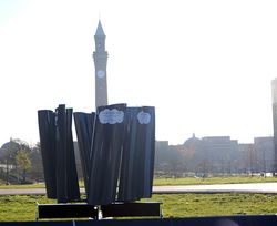 Photograph of the Birmingham Blade,a circle of vertical blades, with Old Joe clock tower in the background