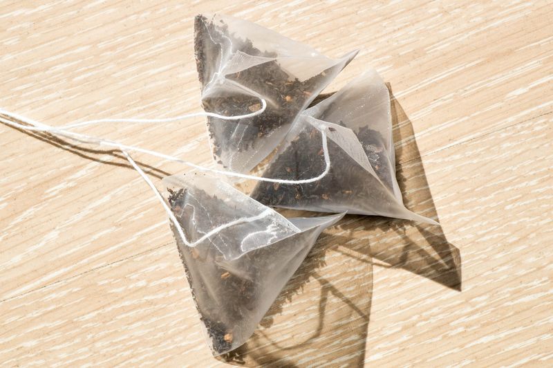 Photograph of three plastic tea pyramid bags on a wooden background