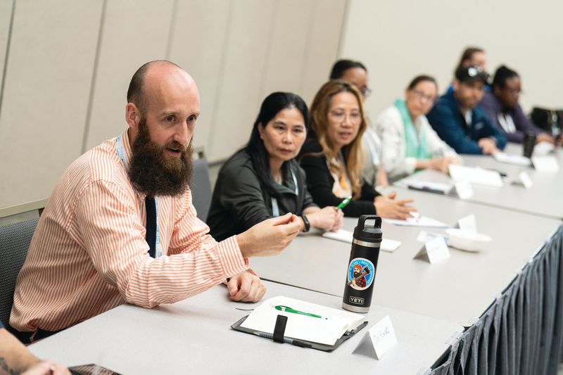 A table of different people sitting in a conference speaking