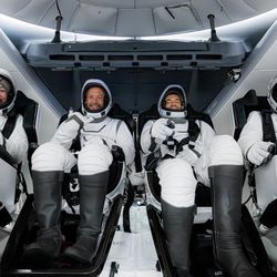 the four astronauts are seen in the capsule smiling and seated