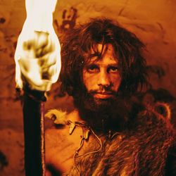 A prehistoric human carrying a torch