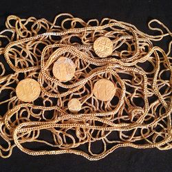 The photo shows five of the now recovered gold coins positioned on a mess of coiled gold chains as a form of display, set against a black background. 