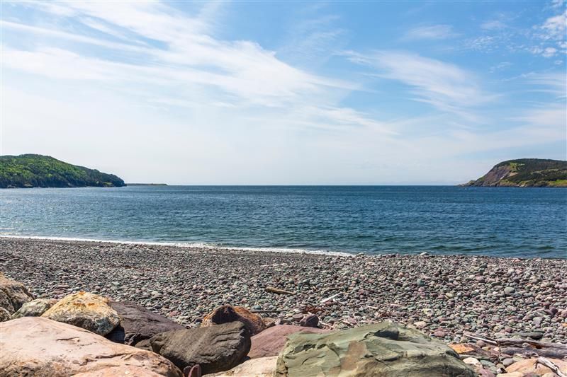 Rocky beach with blue sky and green land masses in the background