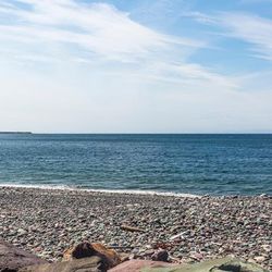Rocky beach with blue sky and green land masses in the background
