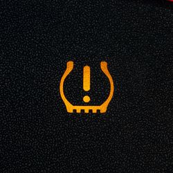 close up of car dashboard with the tire pressure light illuminated in yellow