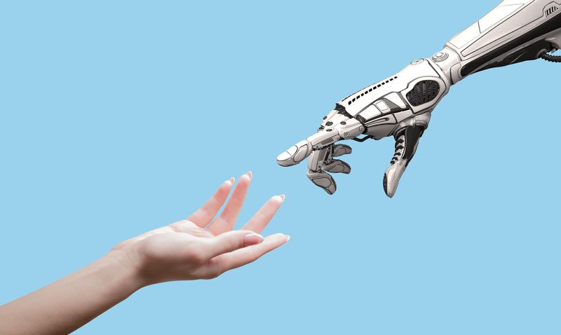 human hand and robot hand stretching towards each other from opposite corners of the image; the background is light blue