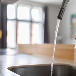 Close up shot of modern kitchen faucet with water running from tap