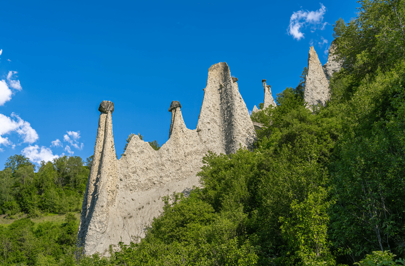 The rock formation called Pyramids of Euseigne stands in the ALps amid Blue skies