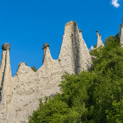 The rock formation called Pyramids of Euseigne stands in the ALps amid Blue skies