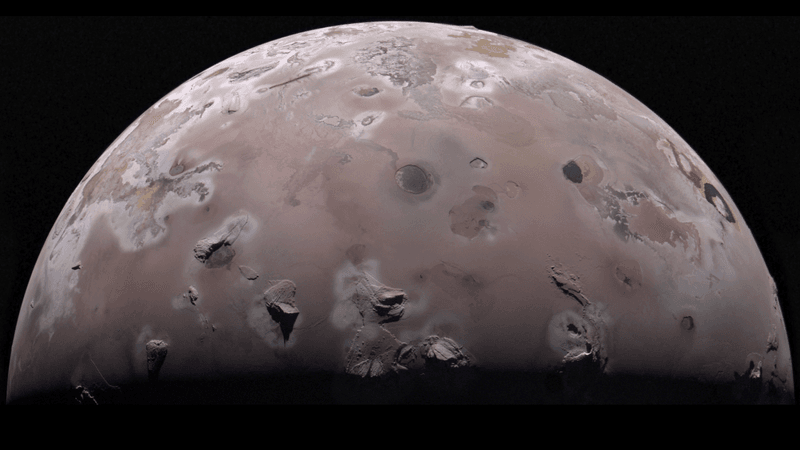 half disk of the moon is visible. volcanoes and laval lakee cover the reddish surface of the moon