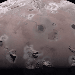 half disk of the moon is visible. volcanoes and laval lakee cover the reddish surface of the moon