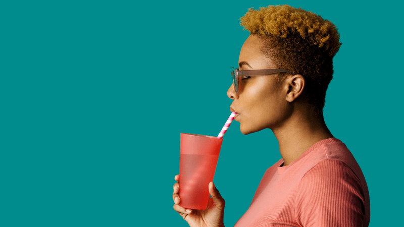 a woman drinking water out of a red cup through a straw