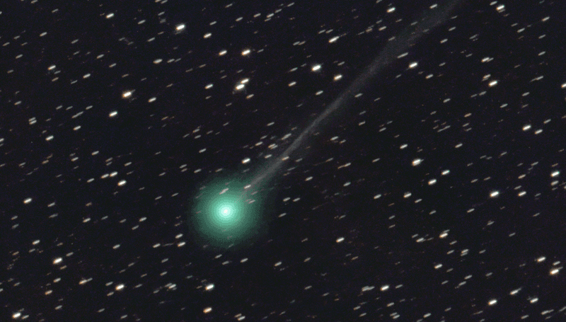 A bright green comet streaks across a star-filled dark backdrop of space