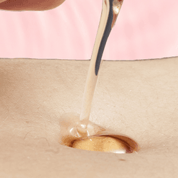 close up of pouring oil into a belly button