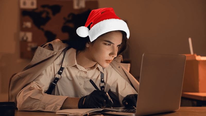 A woman spy working on a computer with a Christmas santa hat.