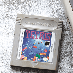 A Tetris cartridge next to a Nintendo Game Boy.